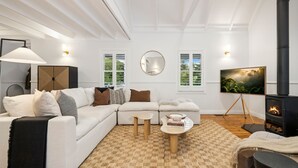 A modern living room with a sectional sofa, a fireplace, a TV, and a large mirror. - Spencer House in Leura (Leura)