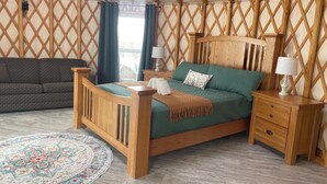 Un dormitorio acogedor con una cama de madera, un sofá verde y una alfombra estampada.