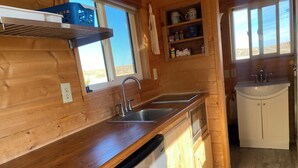 Una cocina compacta con armarios de madera, lavavajillas, fregadero y ventana con vistas al exterior.