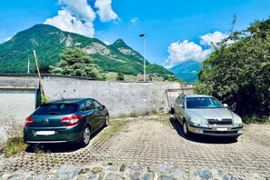Deux voitures sont garées sur une chaussée pavée, avec une chaîne de montagnes en arrière-plan.