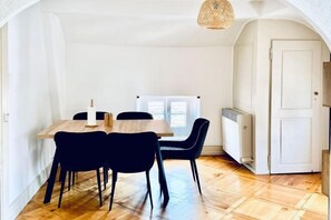 A dining area with a wooden table and black chairs, a white door, and a window with blinds. - Historic House Aigle - Lake & Alps - Garden & BBQ (Aigle)