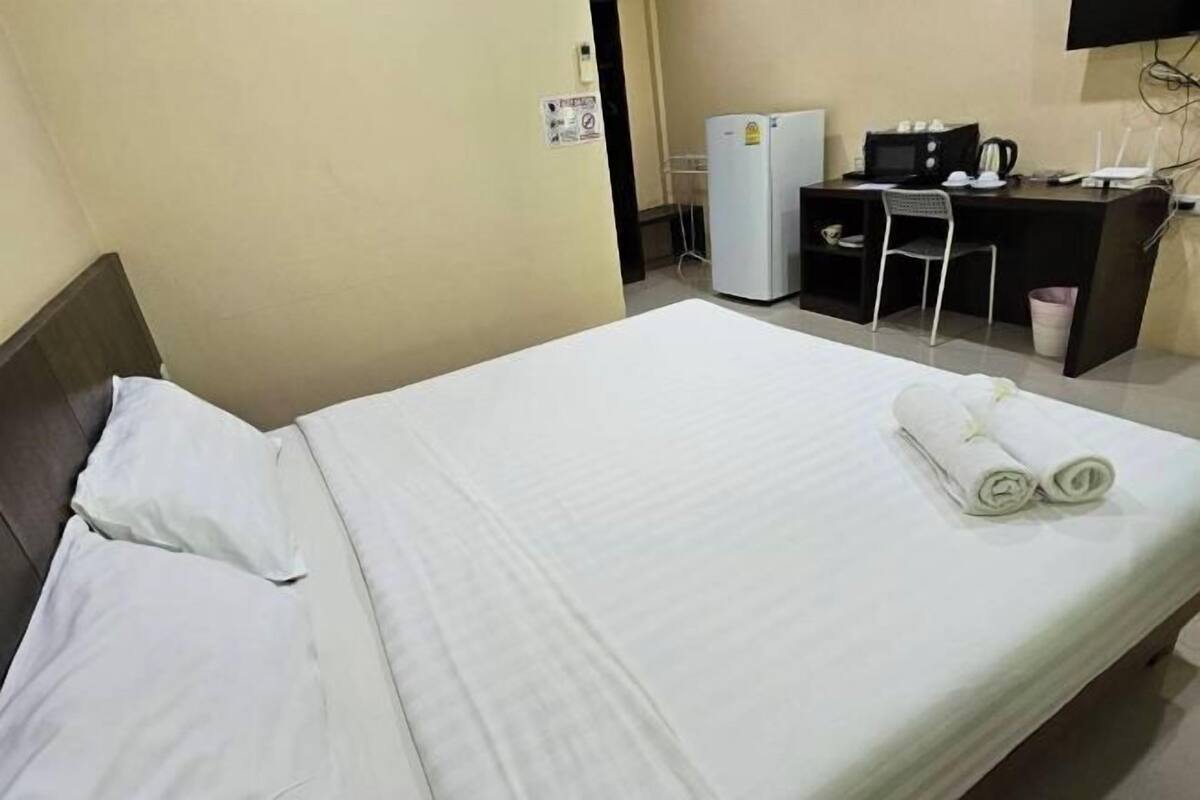 A hotel room with a bed, a desk, a chair, a refrigerator, and a television.