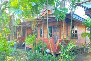 A wooden house with a porch surrounded by tropical vegetation. - Samran Resort (Phuket)
