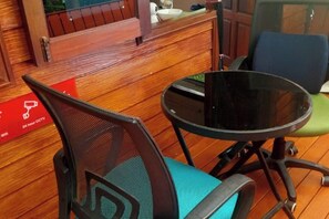 A wooden reception desk with a glass partition, a black round table, and a blue chair. - Samran Resort (Phuket)