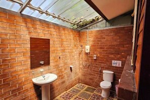 A small, enclosed bathroom with brick walls, a single sink, and a toilet. - Samran Resort (Phuket)