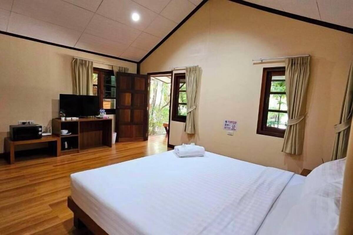 A hotel room with a bed, a TV, a desk, and a window.