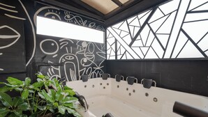 A modern bathroom with a large bathtub, black and white wall art, and green plants. - Luxury Suite - Rooftop, Jacuzzi & Balcony (Medellín)