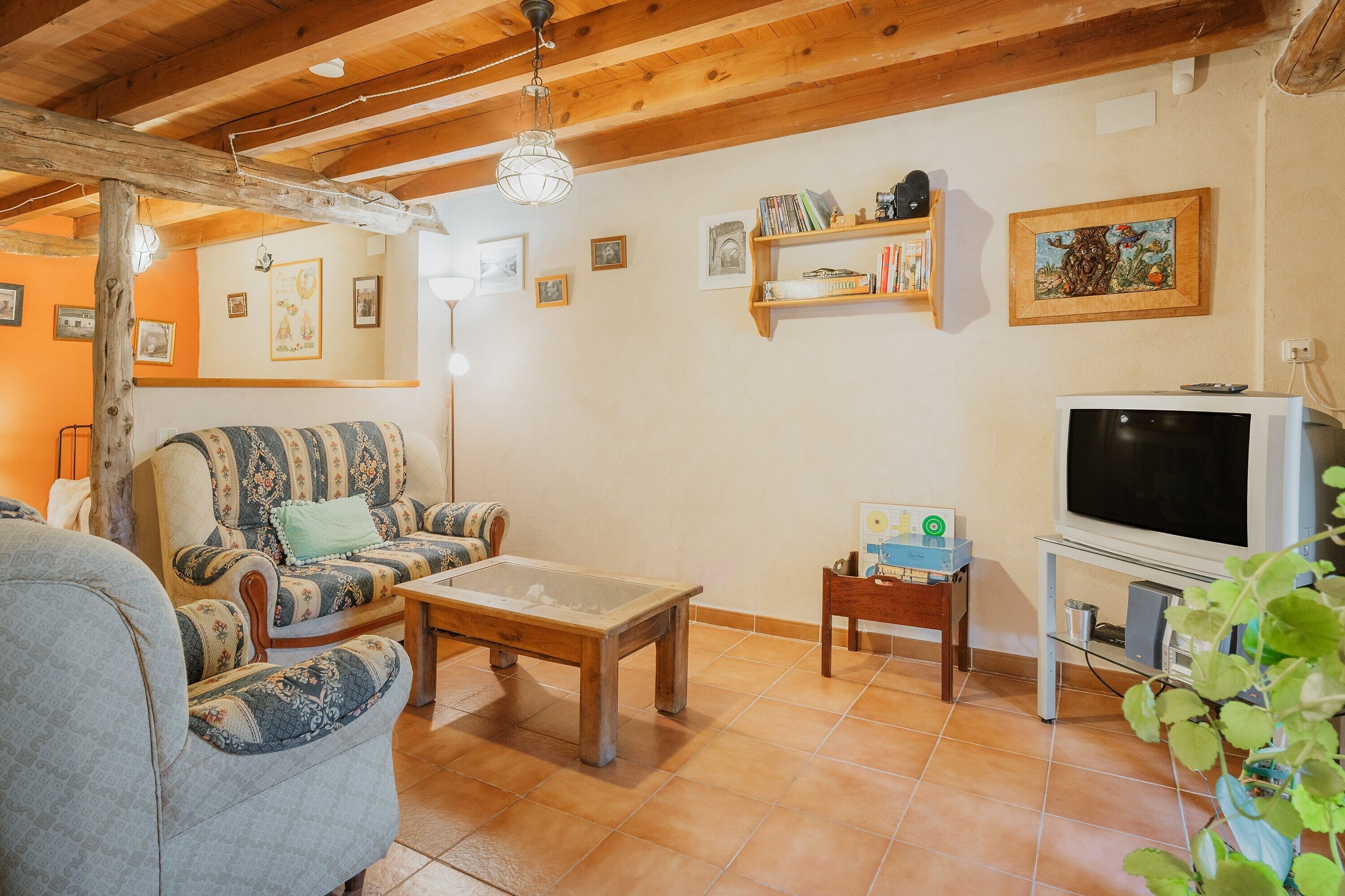 A cozy living room with a sofa, a coffee table, a television, and a bookshelf.