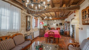 A rustic interior with a wooden ceiling, stone walls, a dining area with a red tablecloth, and a chandelier. - Rural House 'El Escondite De Los Duendes' with Mountain View, Private Garden and Wi-Fi (Tanarro)