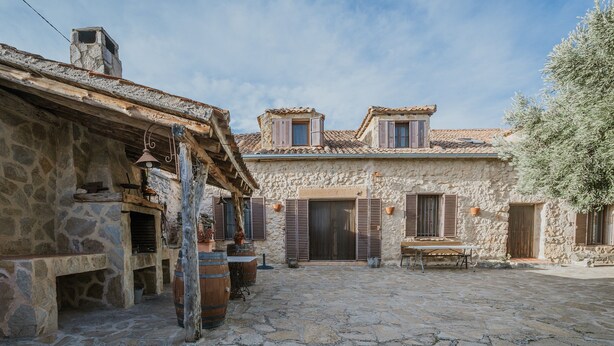 A stone courtyard with rustic buildings, wooden barrels, and a bench. - Rural House 'El Escondite De Los Duendes' with Mountain View, Private Garden and Wi-Fi (Tanarro)