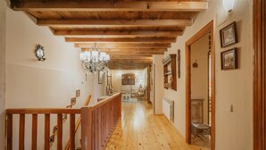 A wooden staircase leading to a room with a chandelier, wooden beams, and framed pictures on the walls. - Rural House 'El Escondite De Los Duendes' with Mountain View, Private Garden and Wi-Fi (Tanarro)