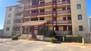 A multi-story building with balconies, a covered entrance, and a parking area. - A nugget with a 180° view of the ocean and its splendid sunsets. (Lacanau)