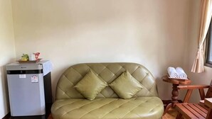 A room with a green leather sofa, a small table with towels, and a compact refrigerator. - Rommaiplaitawan hotel & resort (Nakhon Ratchasima)