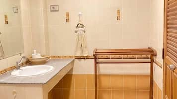 Un bagno con lavandino, specchio, asciugamano e porta asciugamani in legno.