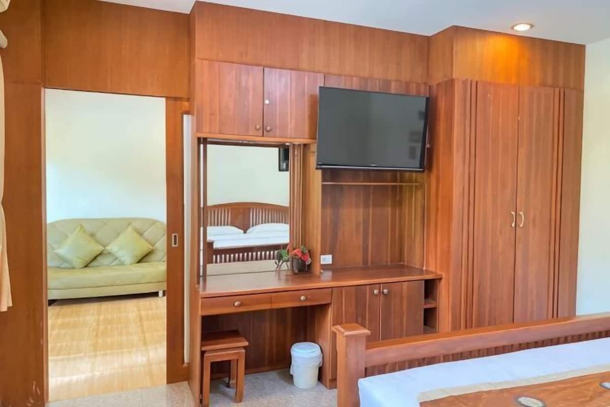 Ein Zimmer mit einem Holztisch, einem Fernseher, einer Couch und einem großen Kleiderschrank.