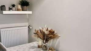 A dining table with a white tablecloth featuring a pumpkin pattern, a vase with dried flowers, and a small golden ornament. - Bright and Cozy 40 m² Apartment at Prague 7 (Prague)