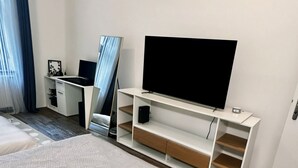 A modern hotel room with a large bed, a desk with a computer, a flat-screen TV, and a built-in shelf. - Bright and Cozy 40 m² Apartment at Prague 7 (Prague)