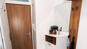 A modern bathroom with a wooden door, white cabinets, a mirror, and a fluffy rug on the floor. - Bright and Cozy 40 m² Apartment at Prague 7 (Prague)