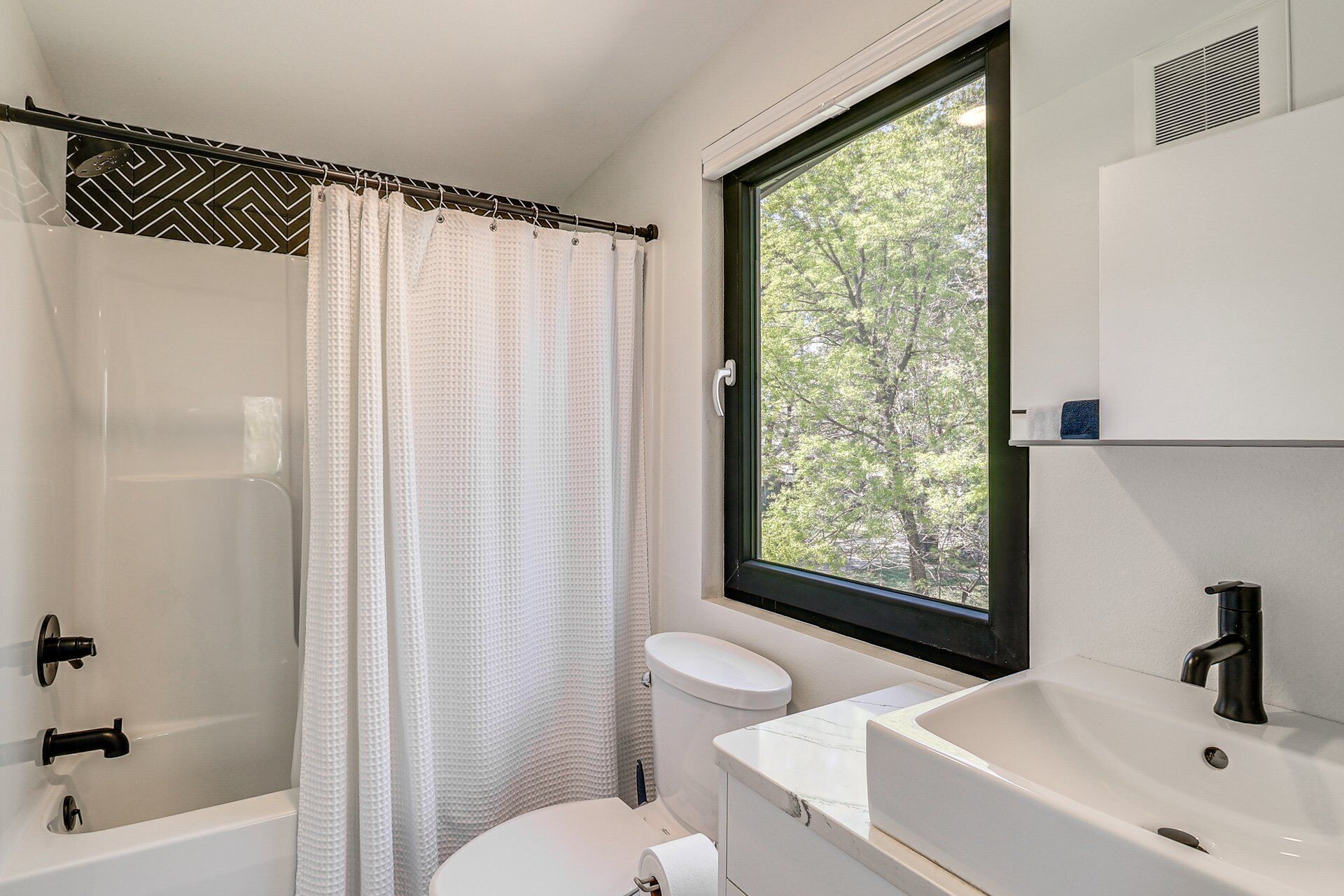 Une salle de bain avec douche, toilettes et lavabo.