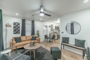 Un salon moderne comprenant un canapé, une table basse et un coin repas avec des chaises.