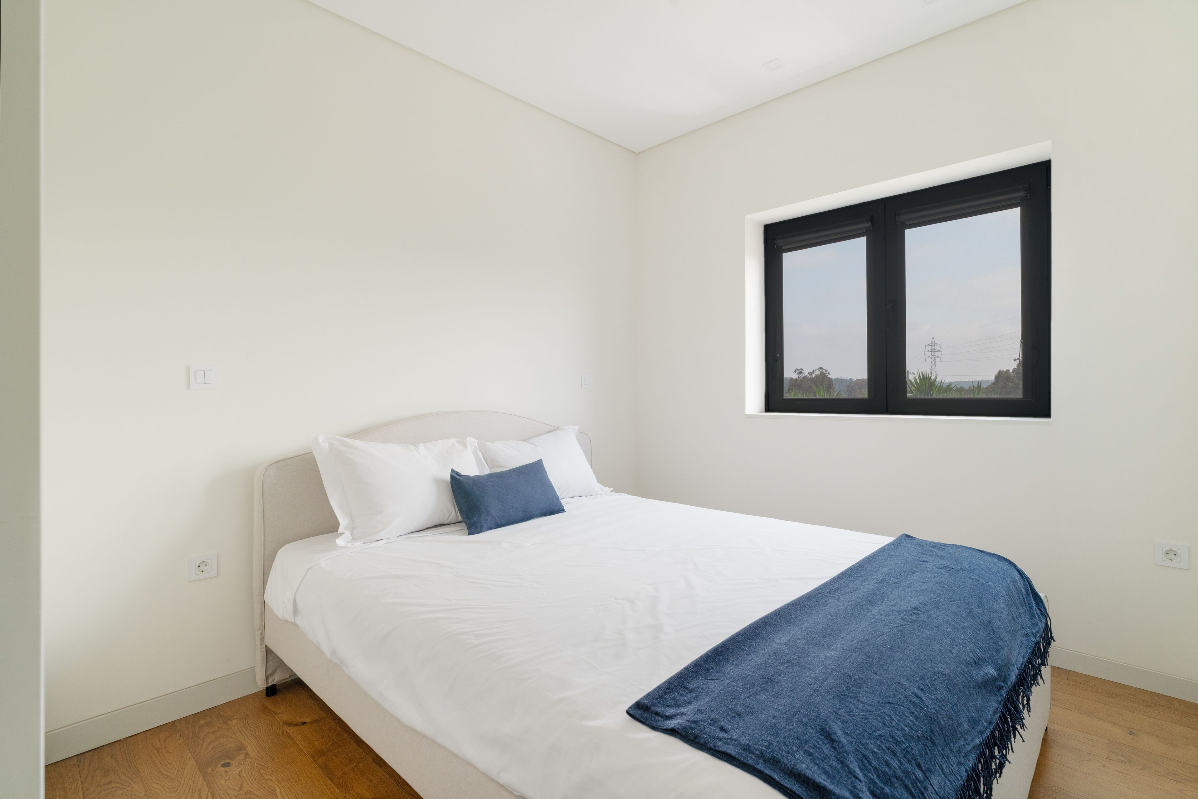 A bedroom with a bed, a window, and a view of the outdoors.