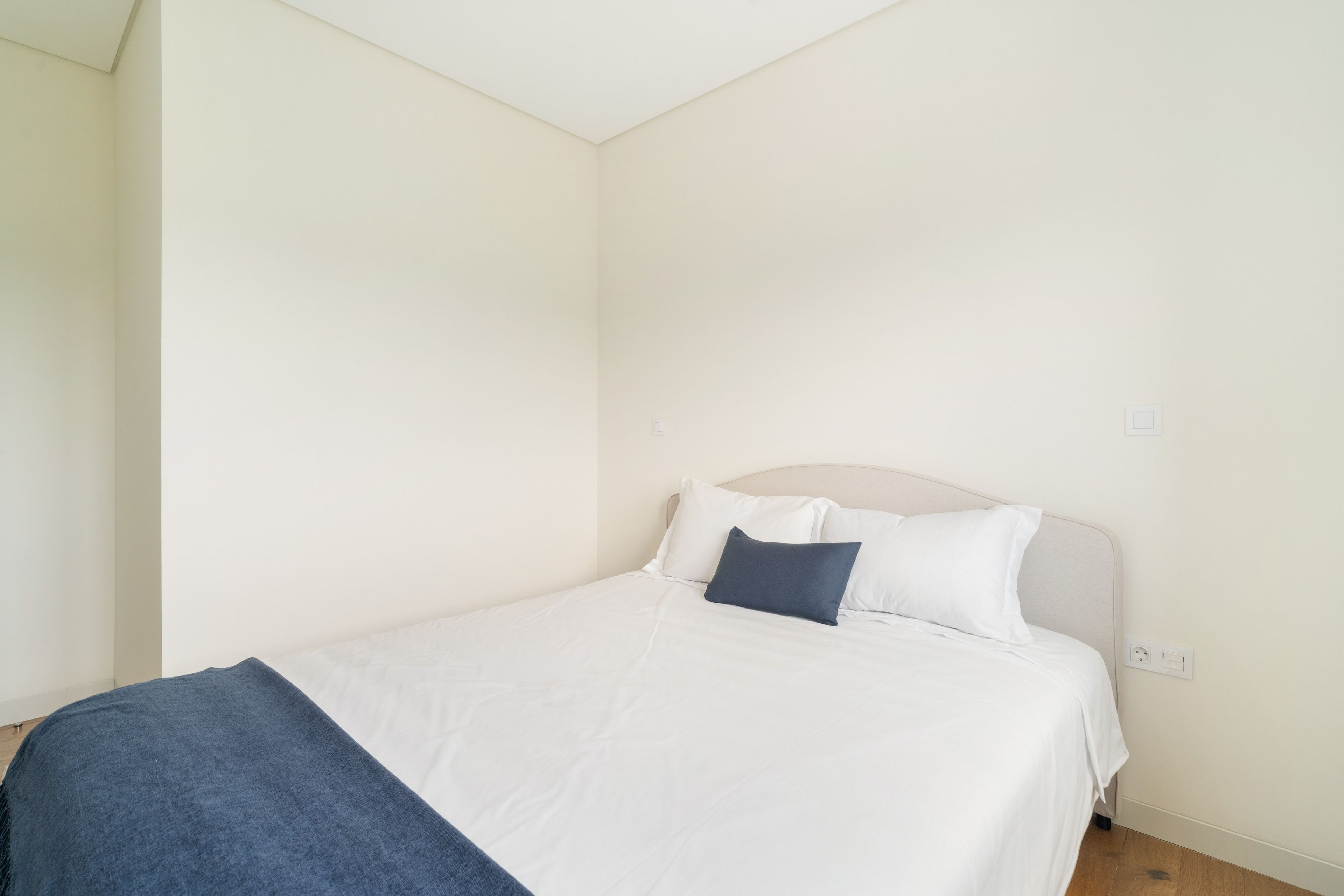 Une chambre à coucher avec un lit, une tête de lit et une prise électrique au mur.