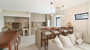 Una cocina moderna con una isla central, taburetes de bar, una mesa de comedor y un sofá.