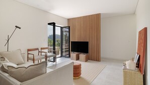 Una sala moderna con un sofá, sillas, un televisor y un ventanal grande.