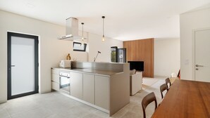 Una cocina moderna con una isla central, horno integrado e iluminación colgante.