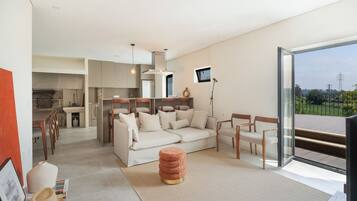 Una sala de estar moderna con sofá, sillones, una mesa de centro y vistas a través de un ventanal.