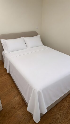 A bed with white bedding in a room with wooden flooring. - Holiday Home 'Picturesque in Northern Portugal' with Private Garden, Balcony and Wi-Fi (Braga)