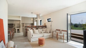 Una sala de estar moderna con sofá, sillones, una mesa de centro y vistas a través de un ventanal.