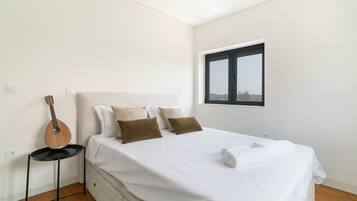 A bedroom with a bed, pillows, a guitar, a window, and a view.