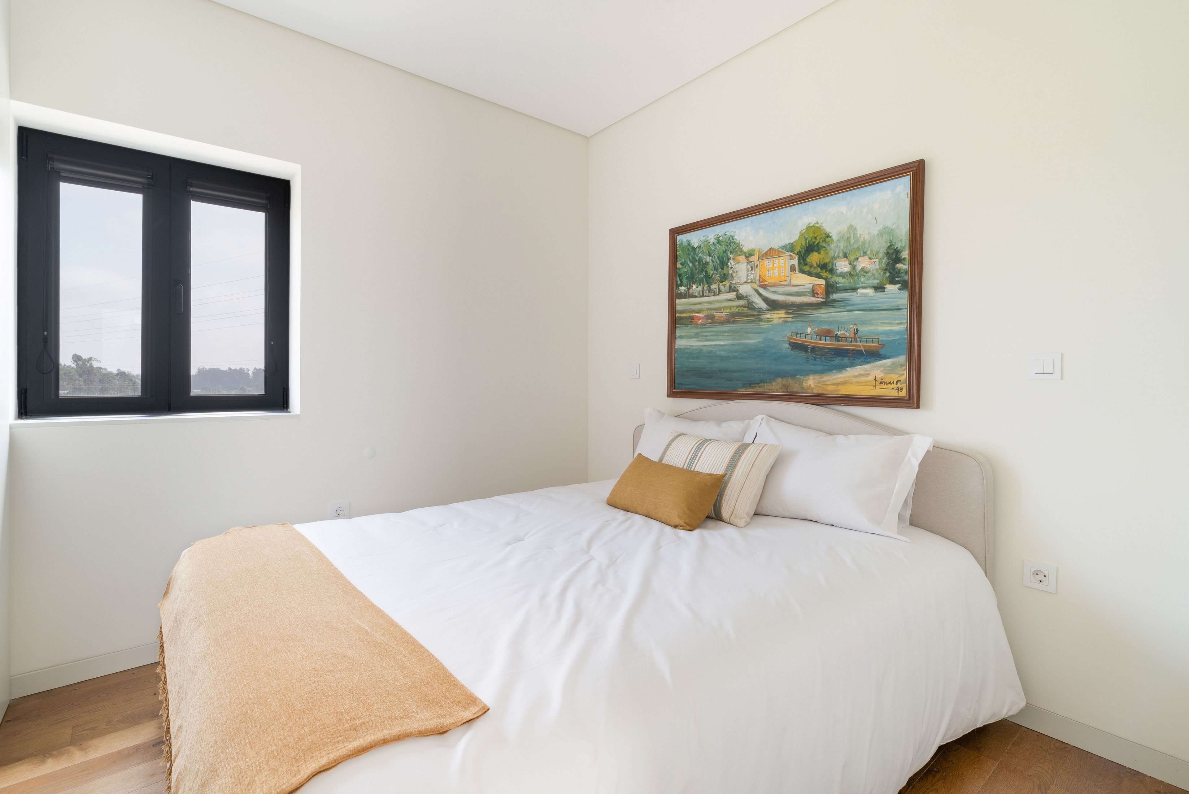Un dormitorio con cama, ventana y un cuadro en la pared.