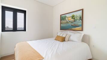 Un dormitorio con cama, ventana y un cuadro en la pared.