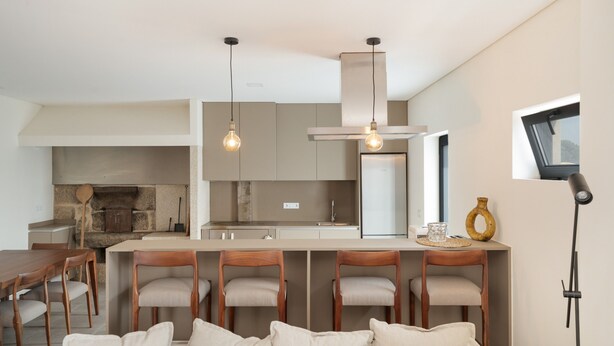 Una cocina moderna con una isla central, sillas de madera e iluminación colgante.