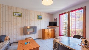 Een kamer met een houten lambrisering, een televisie, een eettafel en een bank.