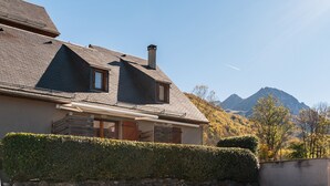 Een huis met schuin dak, schoorsteen en raam.