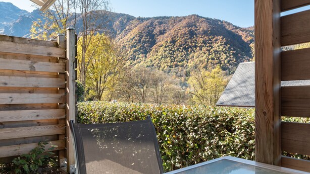 Een houten terras met uitzicht op een berg en herfstkleurige begroeiing.