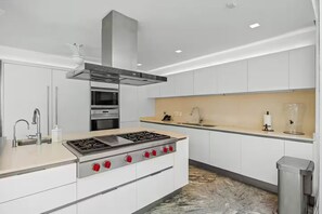 A modern kitchen with a central island, stainless steel appliances, and white cabinetry.