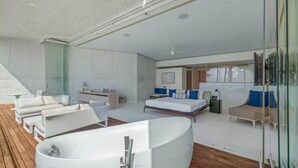 En moderne og rummelig opholdsstue med et stort badekar, en sofasæt og en seng med blå puder.