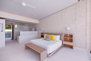 A modern bedroom with a large bed, bedside tables, a bench, and a view of the bathroom.