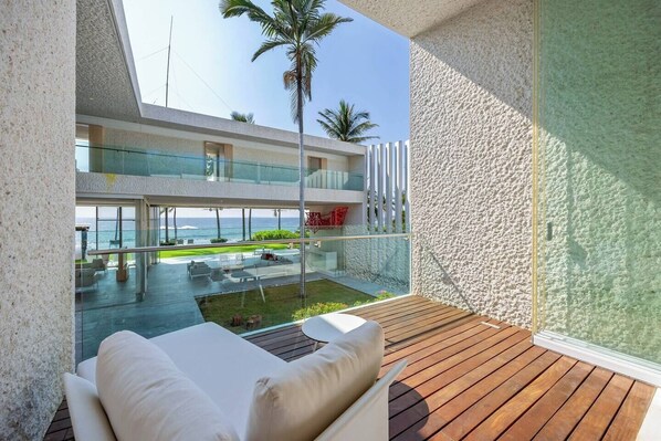 A modern outdoor seating area with a view of a pool and ocean.