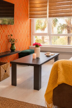 Quarto moderno com parede estampada, janela ampla, mesa com vaso de flores e um sofá.