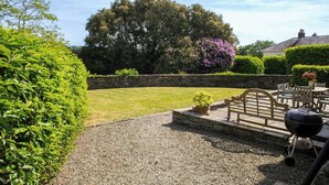 A garden patio with a gravel path, a wooden bench, a table with chairs, and a barbecue grill. - The Dovecote, Llechryd (Llechryd)