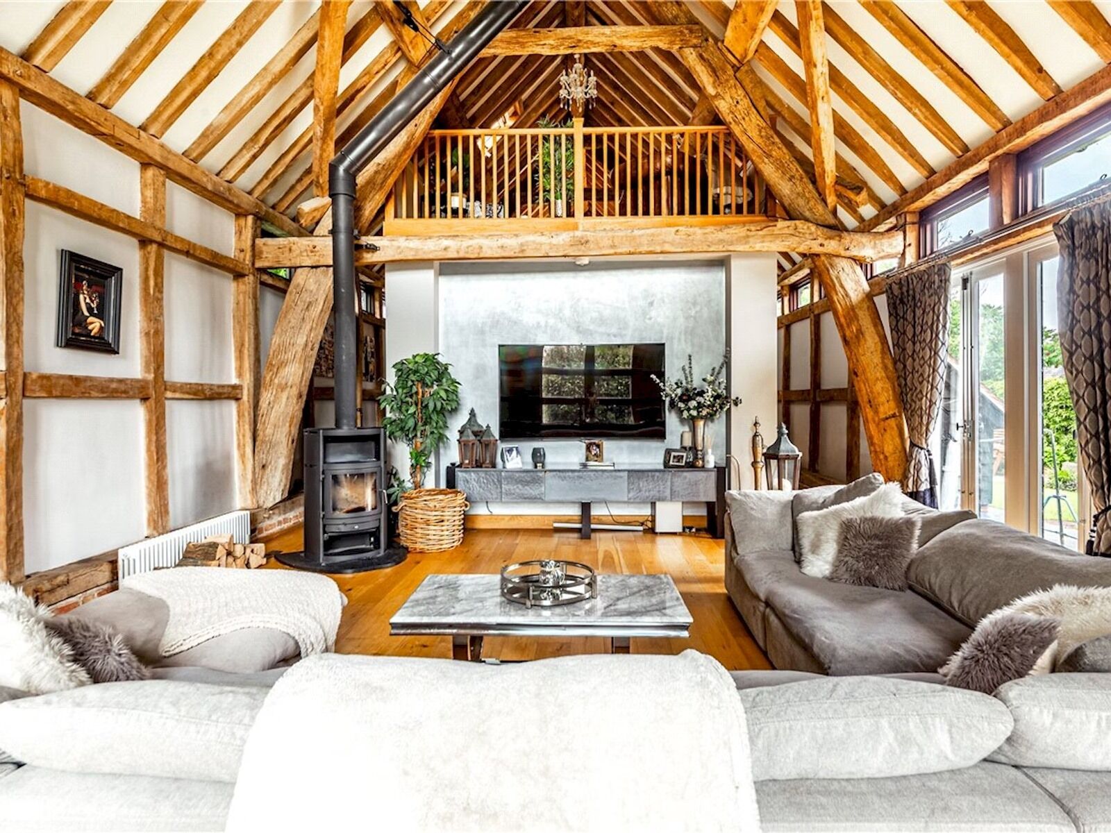 A cozy living room with a fireplace, wooden beams, a sofa, and a TV.