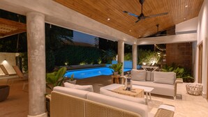 An outdoor patio with a pool, lounge chairs, and a seating area with a sofa and coffee table.