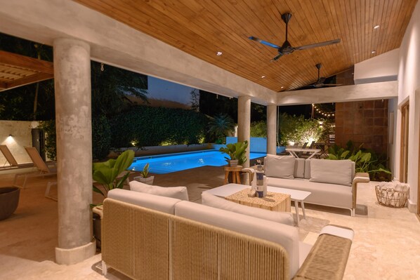 An outdoor patio with a pool, lounge chairs, and a seating area with a sofa and coffee table.