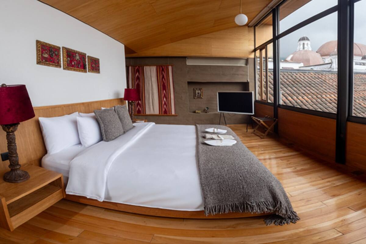Una camera da letto moderna con un grande letto, pavimento in legno, televisione e vista su edifici a cupola.