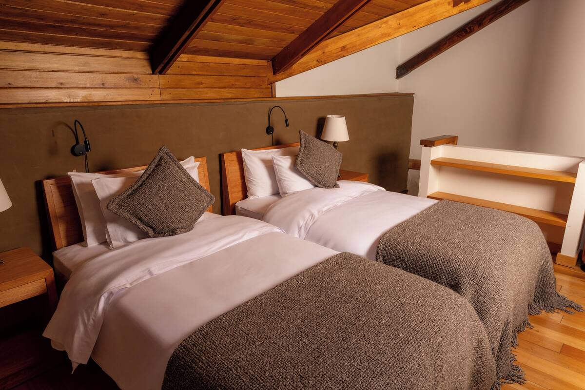 Camera da letto con due letti e testiere e soffitto in legno.